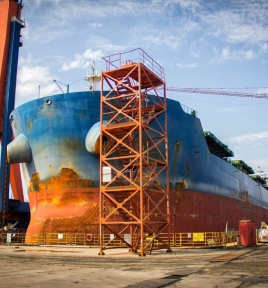 a-large-tanker-cargo-ship-is-being-renovated-and-painted-in-shipyard-dry-dock-e1665494792853